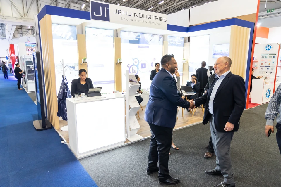 The Jehu Industries exhibition stand with overhead branding and people greeting one another.