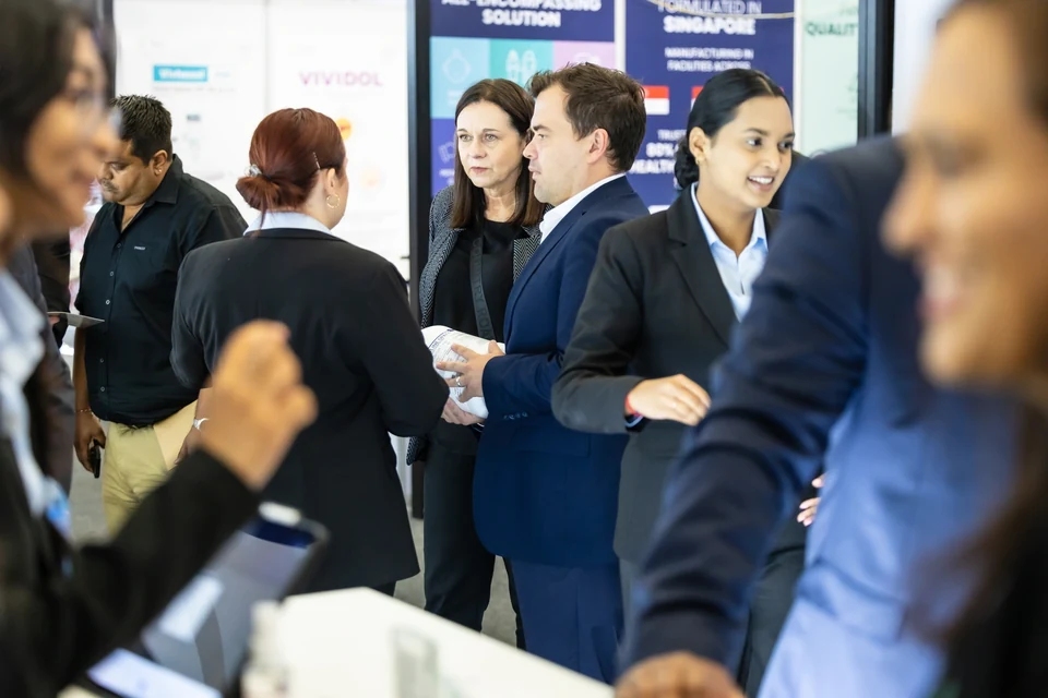 Visitors and staff in conversation, with printed product information being held at the stand.