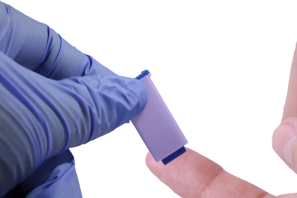 Edited close up of a lancet held against a fingertip