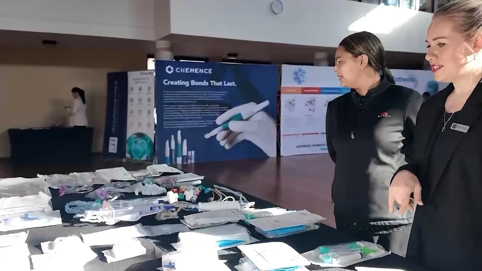 A staffed product table with samples, information sheets and a branded screen.